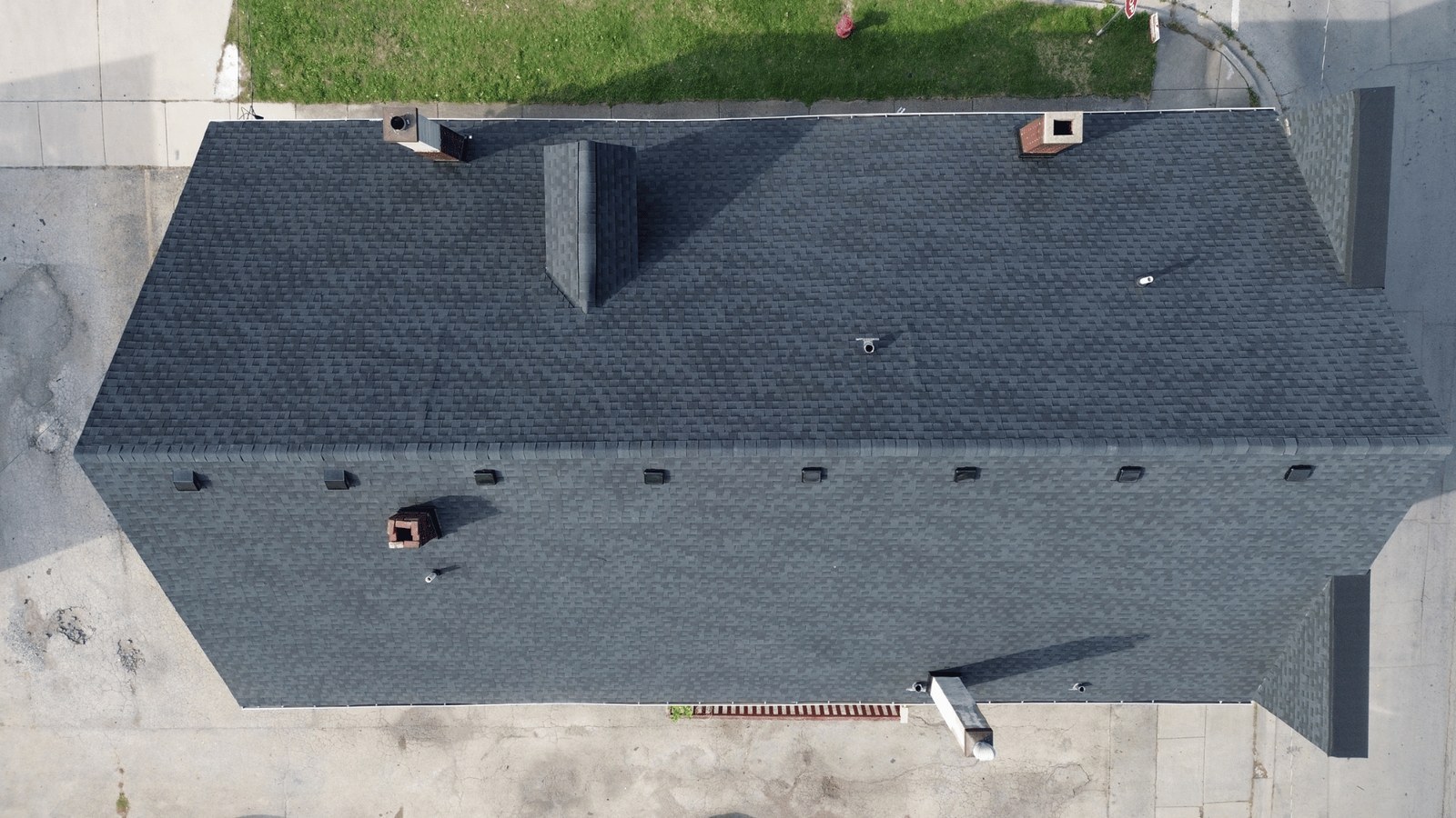 Drone view straight down on a new dark shingle roof with vents