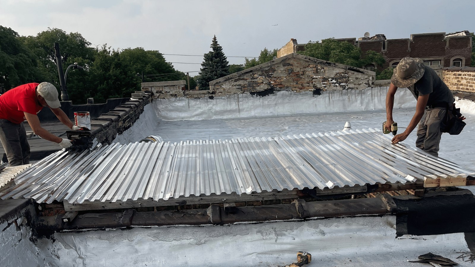 Crew installing corrugated panels on a flat roof with Chicago rooftops behind