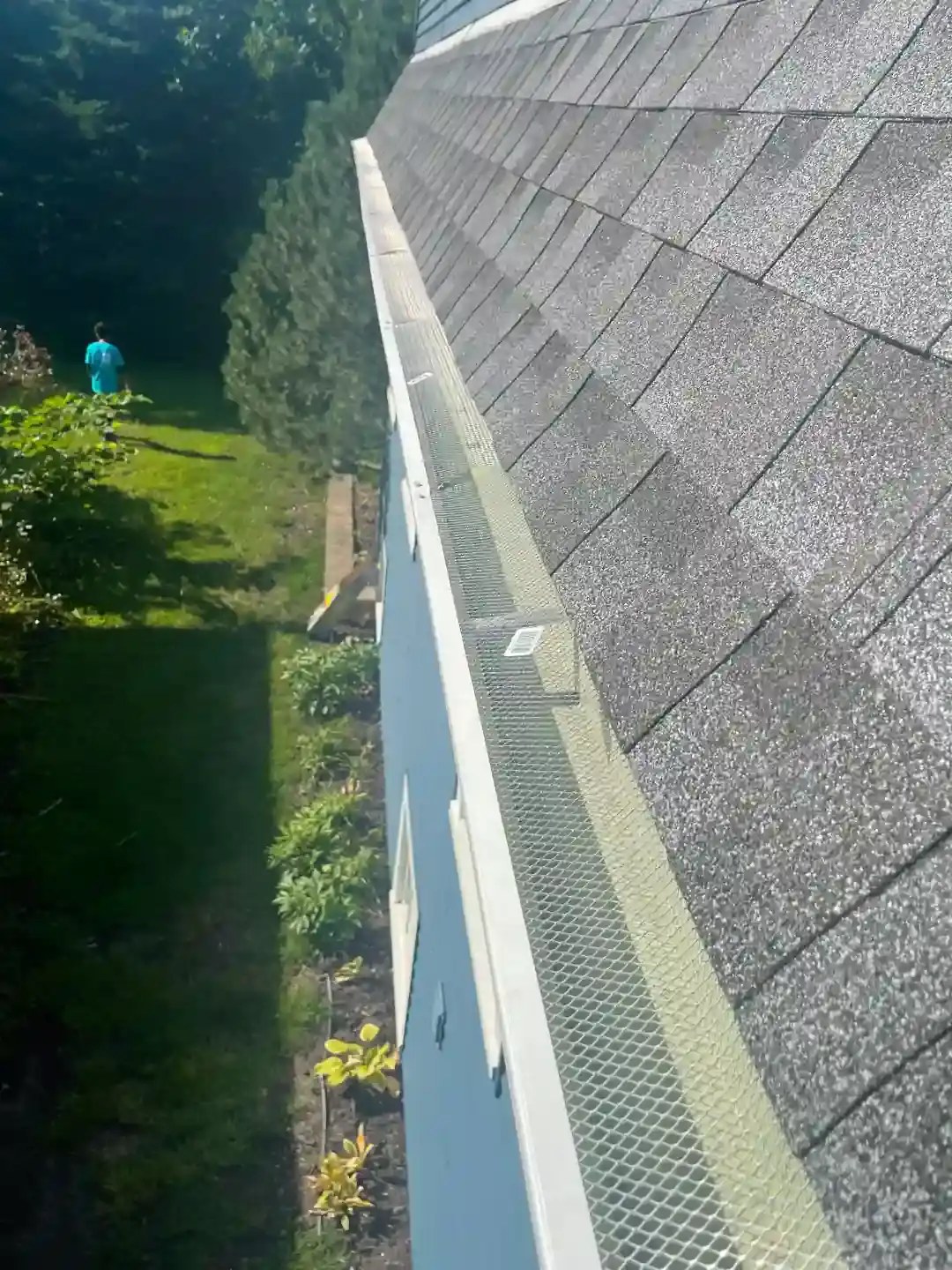 New gutter with mesh gutter guard along a shingle edge
