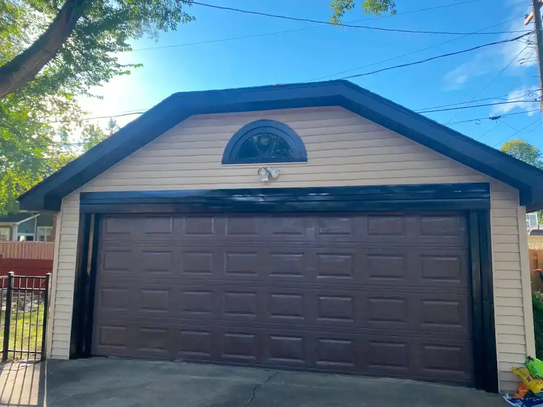 Detached garage with new tan siding and black trim