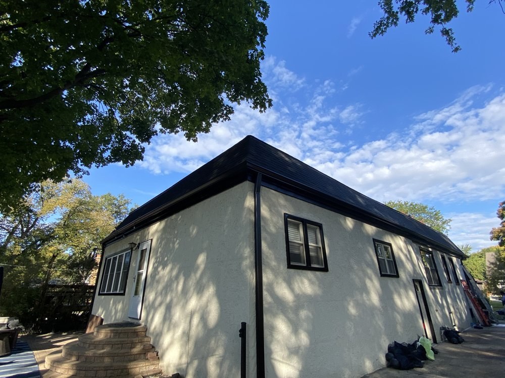 Stucco two-flat with a new black roof edge and fascia